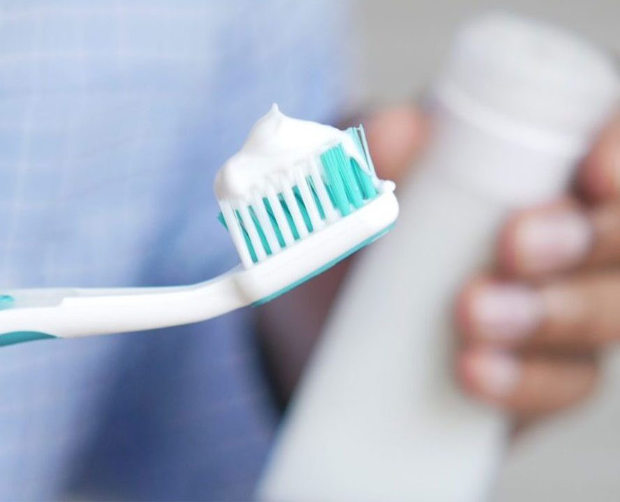 Tootbrush-with-toothpaste-and-blurry-background Sunscreen held in hand at beach